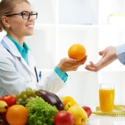 A doctor presenting a woman with an orange, promoting healthy hair loss solutions.