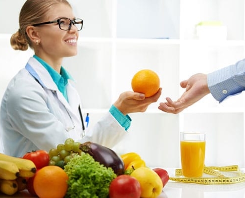A doctor presenting a woman with an orange, promoting healthy hair loss solutions.