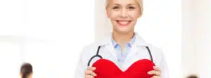 A female doctor holding a heart with a stethoscope while discussing seasonal hair loss.