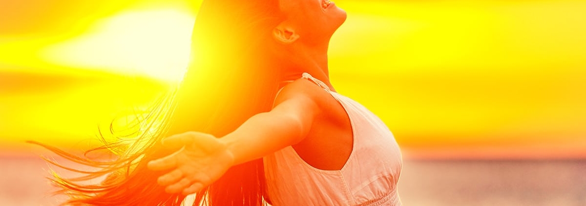 A woman with her arms outstretched at sunset, showcasing a fresh new summer style.