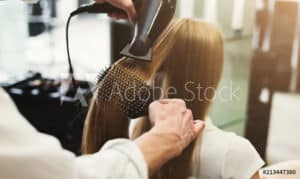 A man is drying a woman's hair in a salon, ensuring proper treatment for her hair.