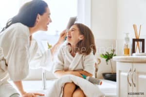 Mother and daughter bonding with a relaxing bath in the bathroom while discussing hair thinning and possible treatment methods.