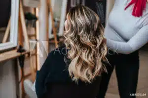 A woman experiencing hair thinning getting her hair done in a salon.