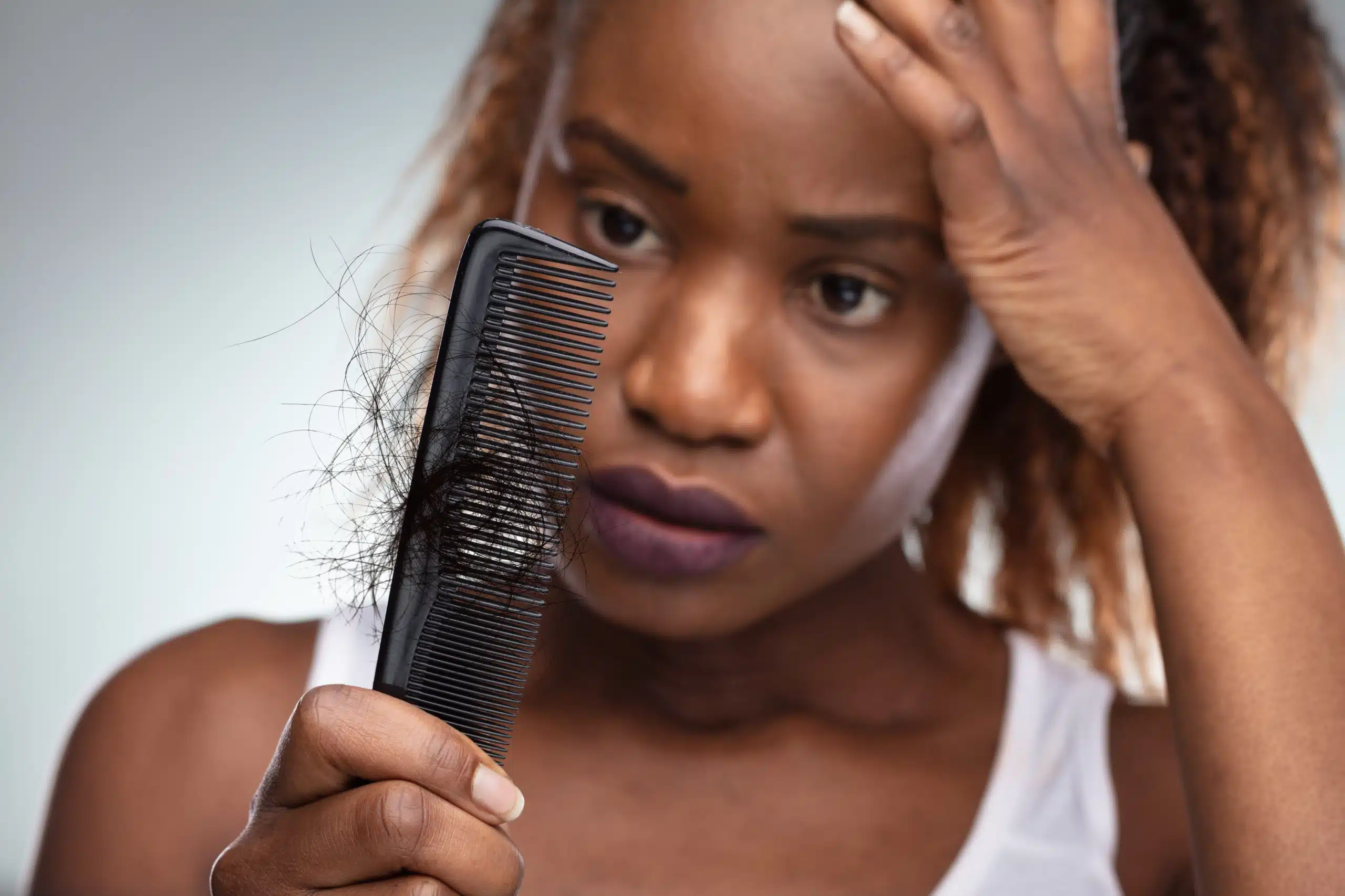 A woman is gently combing her hair with a comb.