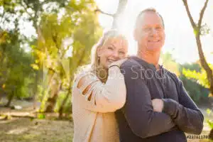 A radiant couple posing in a park, exuding joy and happiness.