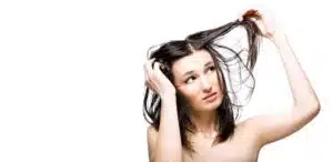 A woman with trichotillomania is combing her hair on a white background.