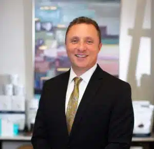 A man in a suit and tie standing in an office, developing a customized treatment plan for hair restoration.