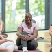 A diverse group of adults smiling while sitting on yoga mats