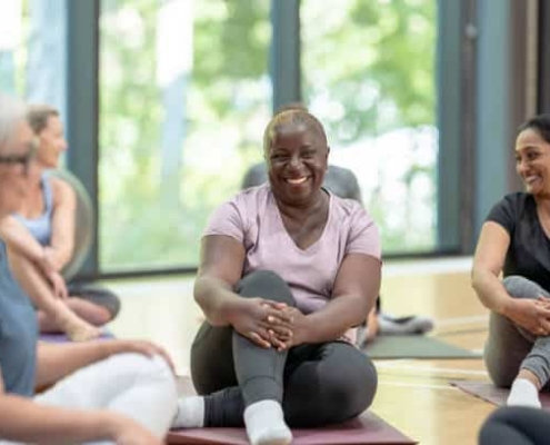 A diverse group of adults smiling while sitting on yoga mats