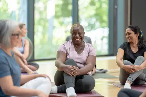 A diverse group of adults smiling while sitting on yoga mats
