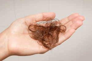 A person's hand holding a piece of hair, emphasizing the importance of hair vitamins.