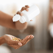 A female pouring out hair vitamins from a white bottle