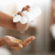 A female pouring out hair vitamins from a white bottle