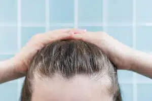 A woman is naturally styling her hair with her hands.