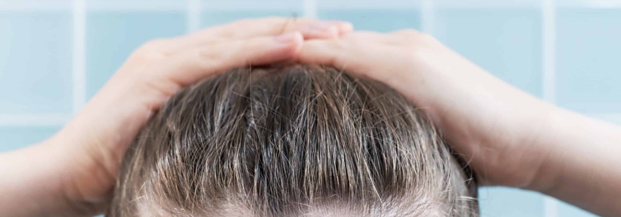 A woman is naturally styling her hair with her hands.
