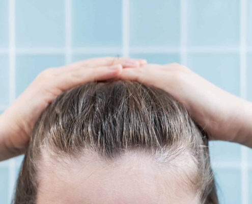 A woman is naturally styling her hair with her hands.