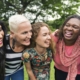 A group of women laughing together in a park, unaffected by hormonal imbalances or hair loss.