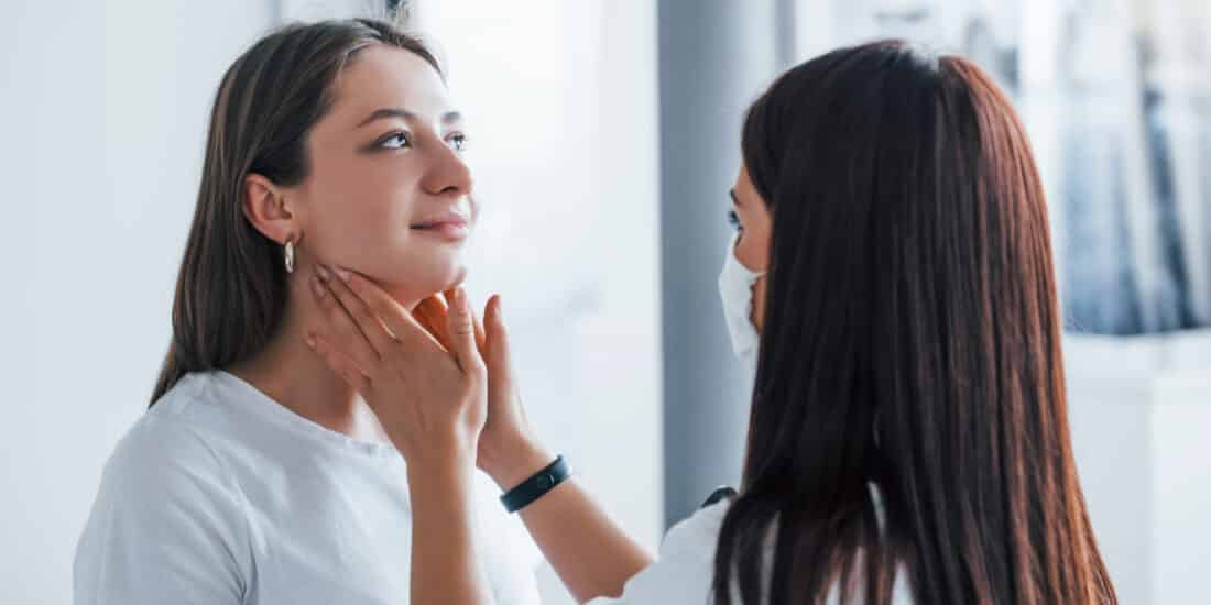 A doctor is examining a woman's neck to assess her thyroid health and investigate possible causes of hair loss.