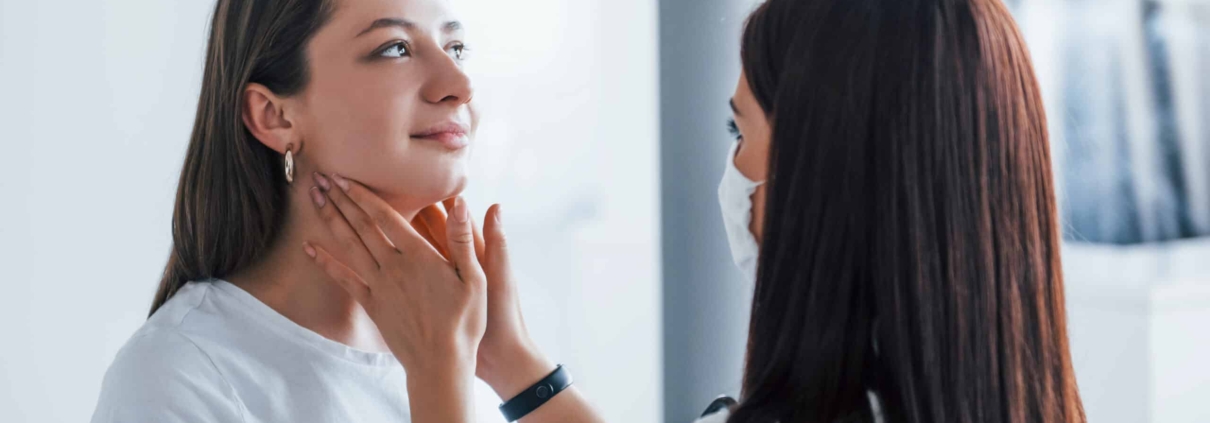 A doctor is examining a woman's neck to assess her thyroid health and investigate possible causes of hair loss.