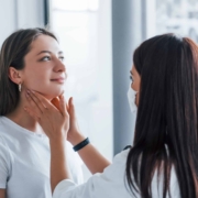 A doctor is examining a woman's neck to assess her thyroid health and investigate possible causes of hair loss.