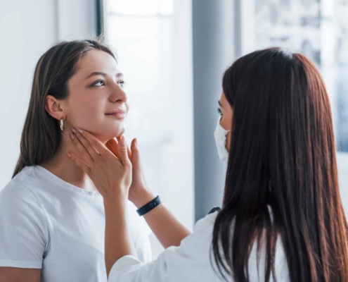 A doctor is examining a woman's neck to assess her thyroid health and investigate possible causes of hair loss.
