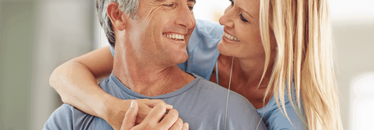 A man and woman happily hugging in front of a laptop.