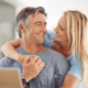 A man and woman happily hugging in front of a laptop.