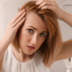 Woman looking in the mirror, gently touching her hair, conveying emotion and reflection